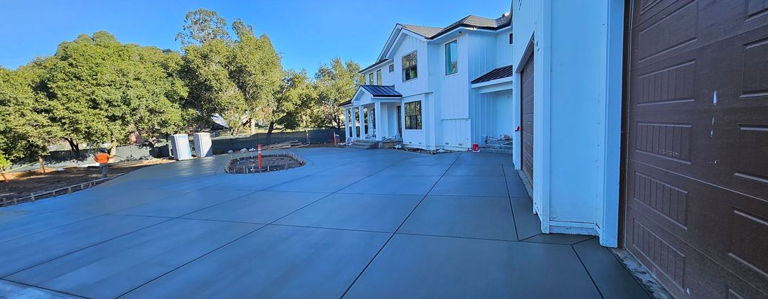 Modern house driveway with blue siding, brown garage door, and trees in the background
