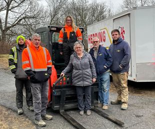 A group of people are standing in front of a forklift.