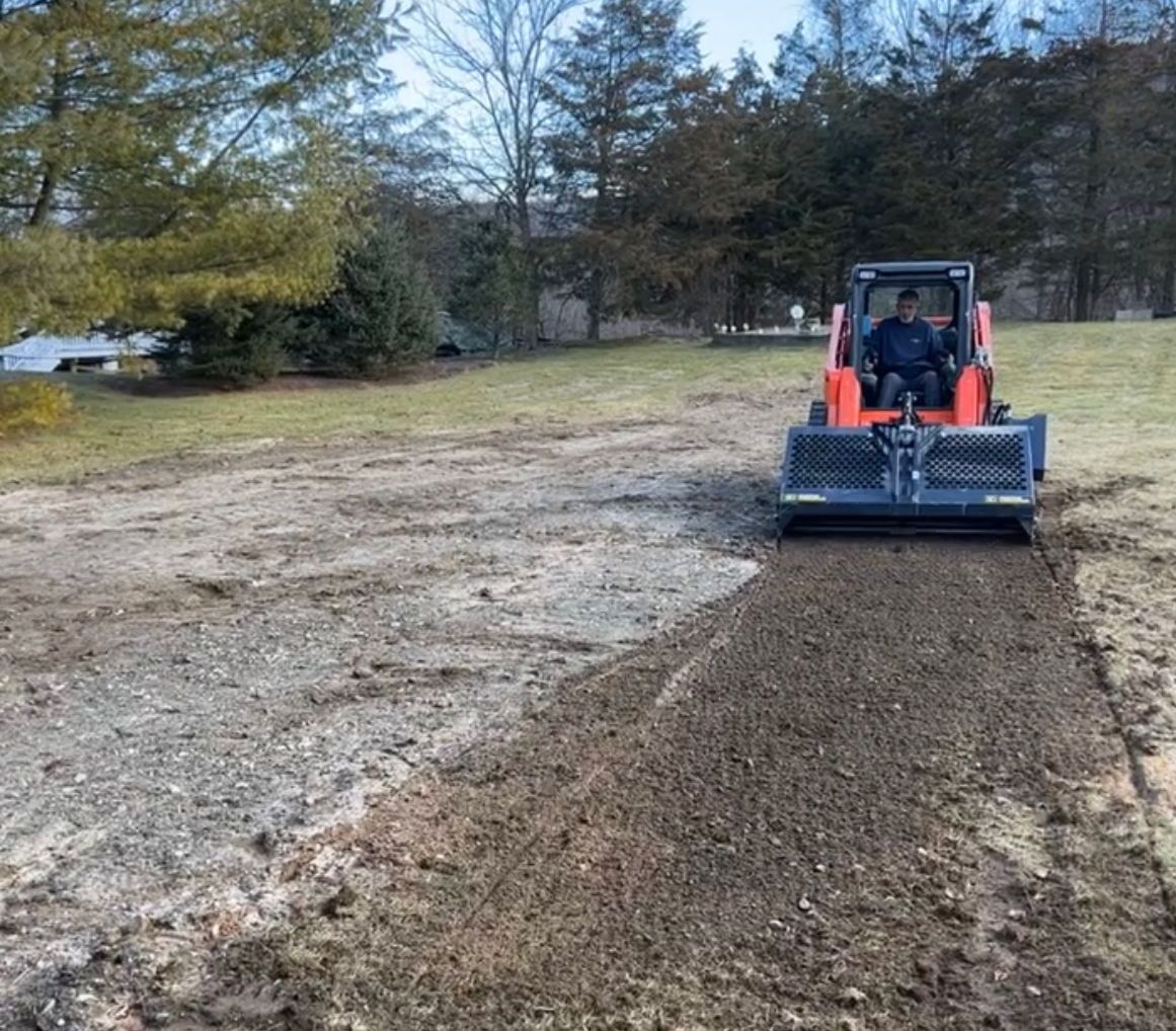 A man is driving a tractor on a dirt road