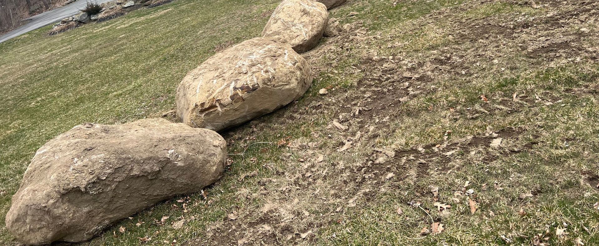 A row of rocks sitting on top of a lush green field.