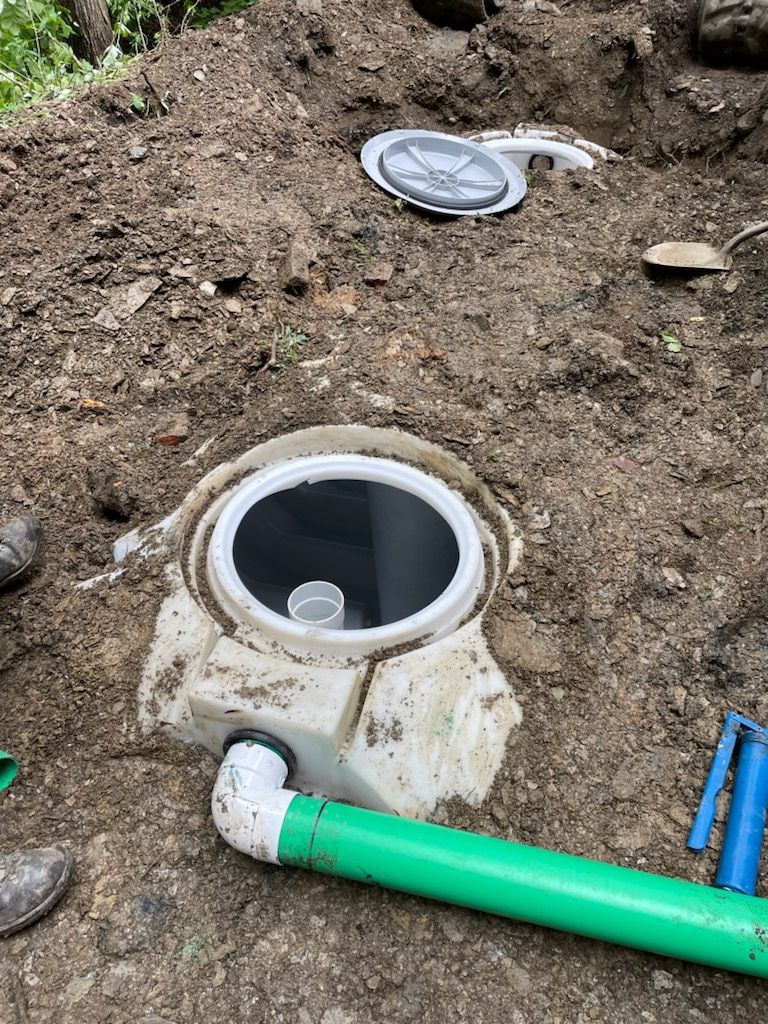A green pipe is sitting next to a drain in the dirt.