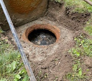A hole in the ground with a shovel in it.
