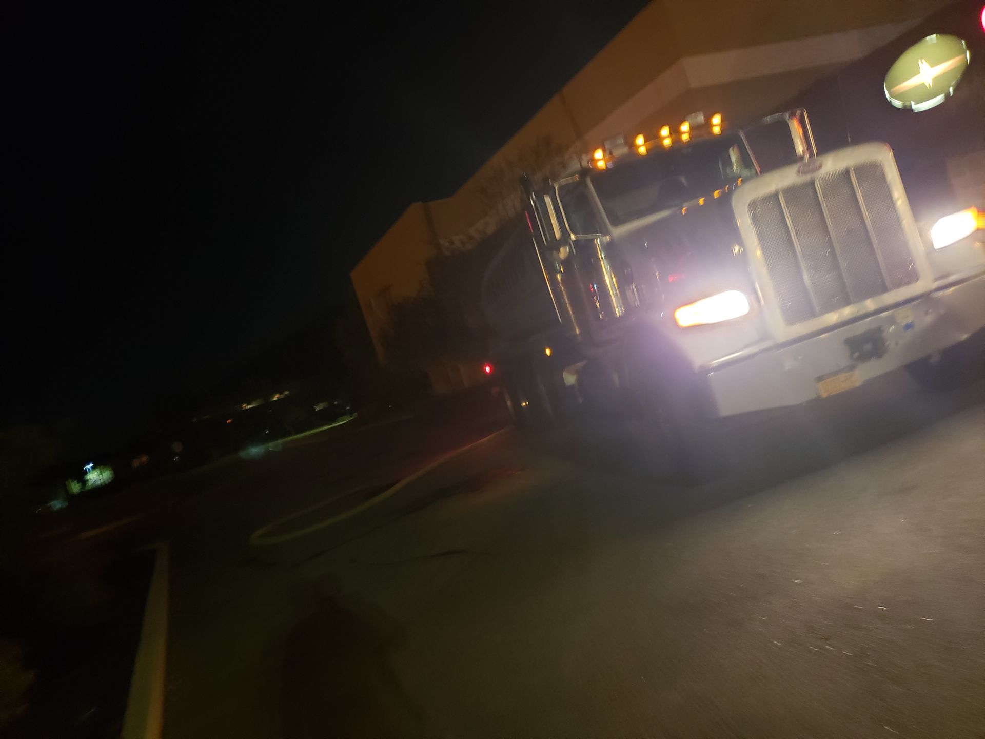 A semi truck is parked in front of a building at night.