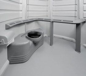 A black and white photo of a portable toilet in a room.