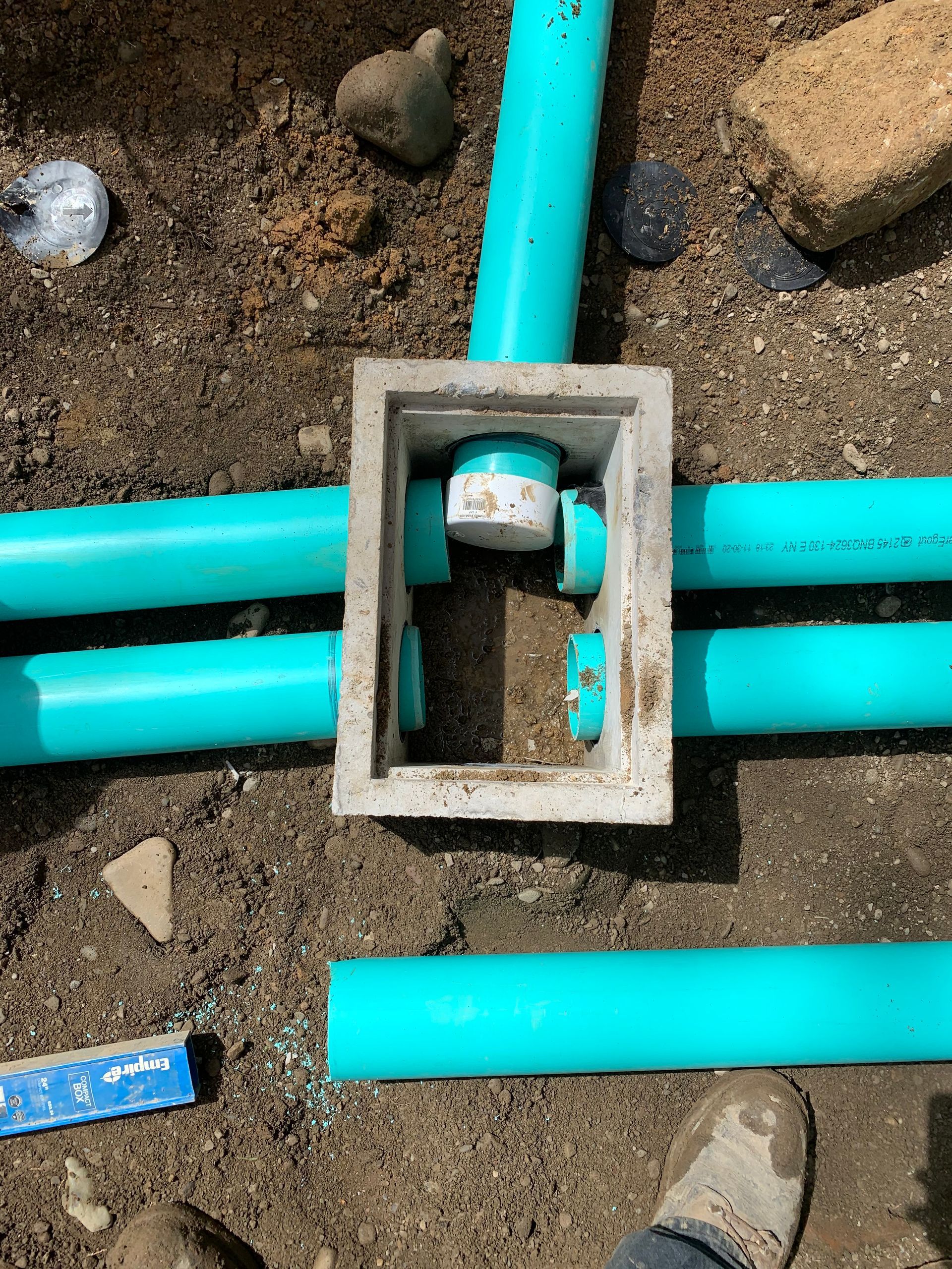 A person is standing next to a concrete box surrounded by green pipes.