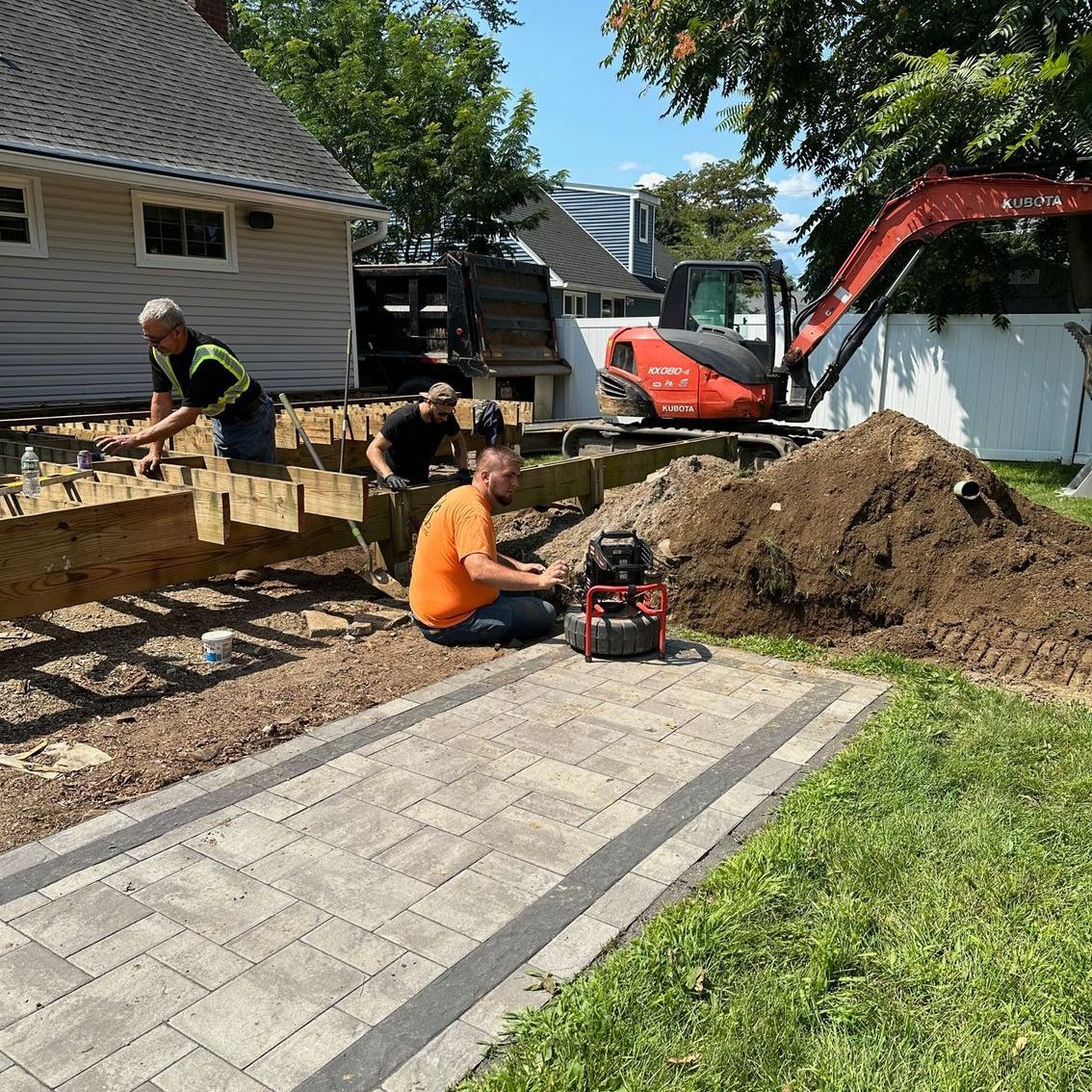 A group of men are working on a sidewalk in front of a house.