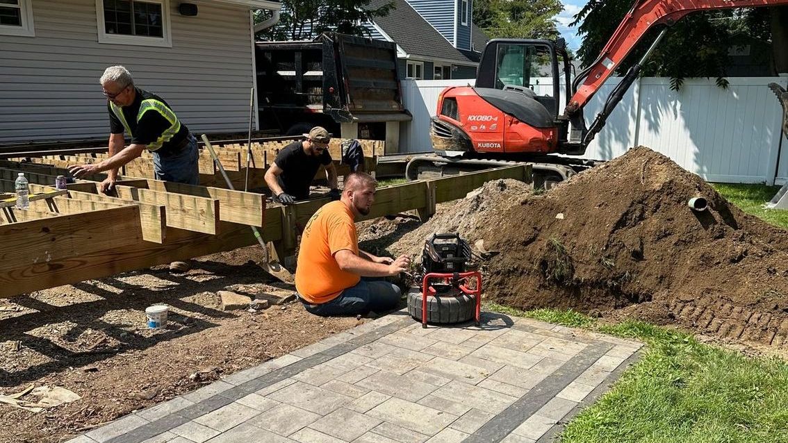 A group of men are working on a construction site in front of a house.