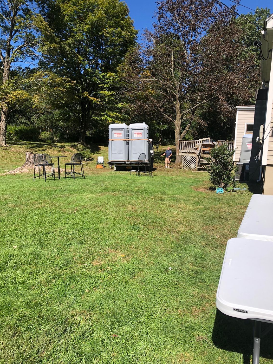 A couple of portable toilets are parked in a grassy field.