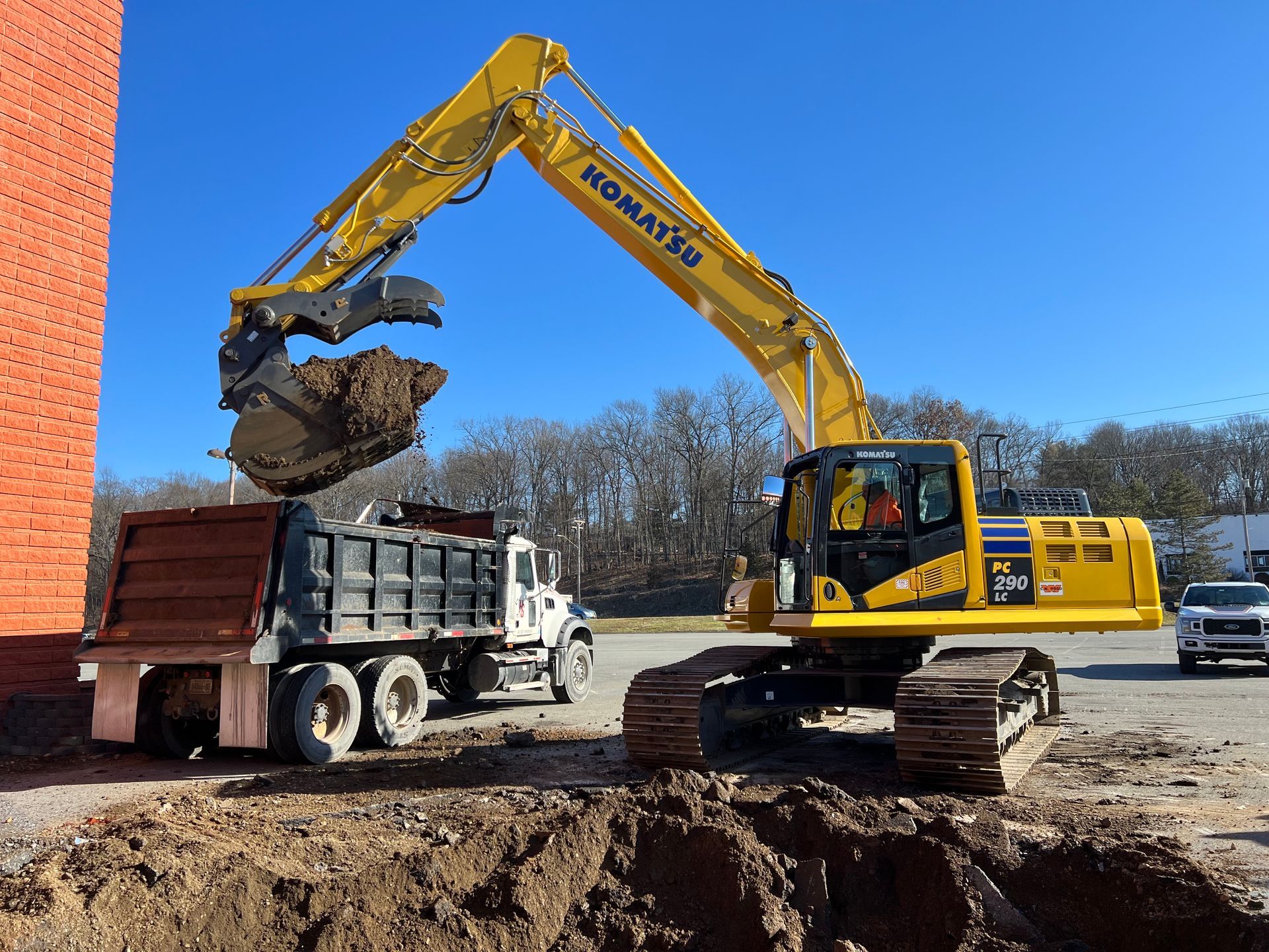 A komatsu excavator is loading dirt into a dump truck.