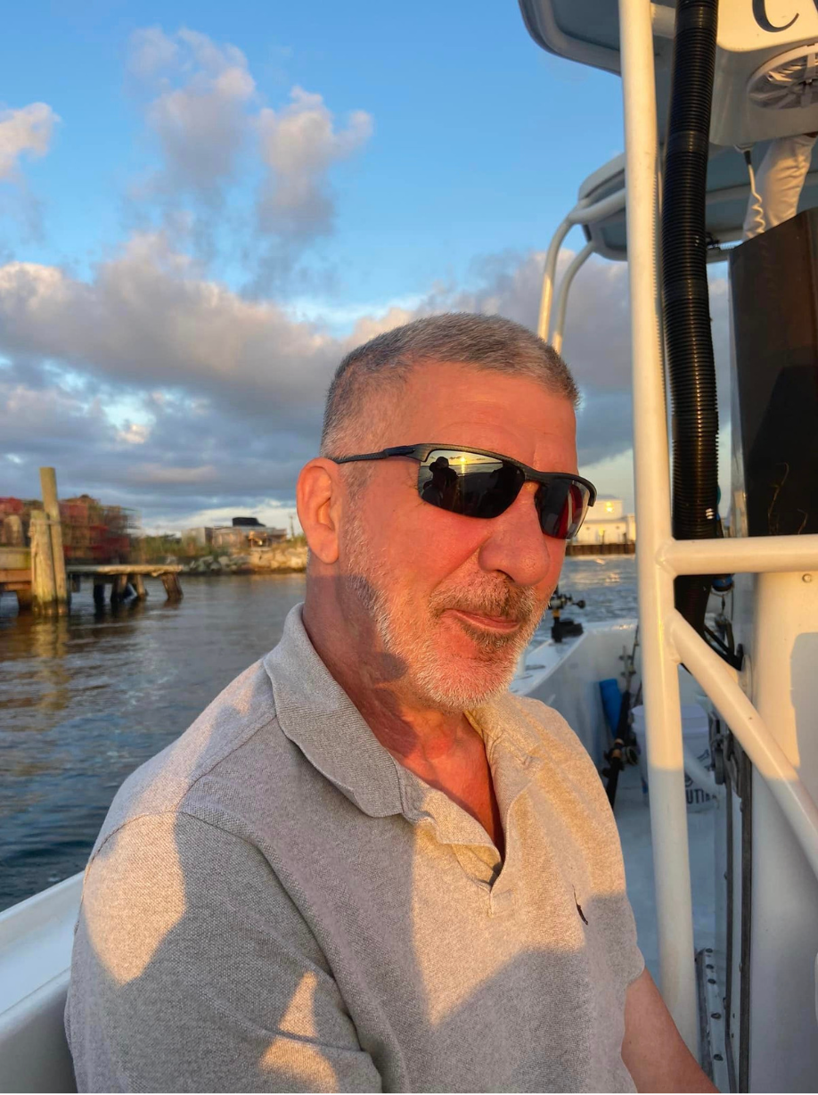 A man wearing sunglasses is sitting on a boat
