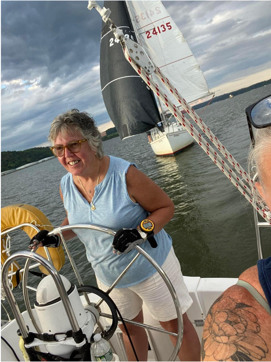 A woman is steering a sailboat in the water.