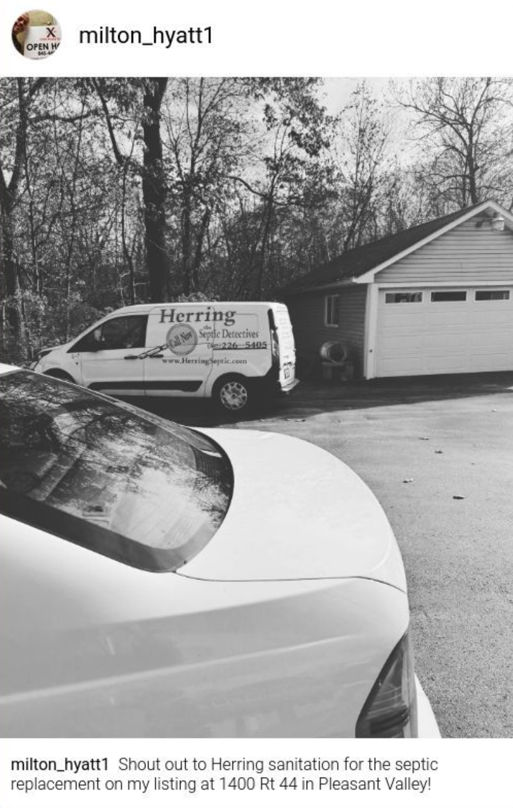 A black and white photo of a car and a van parked in front of a garage.