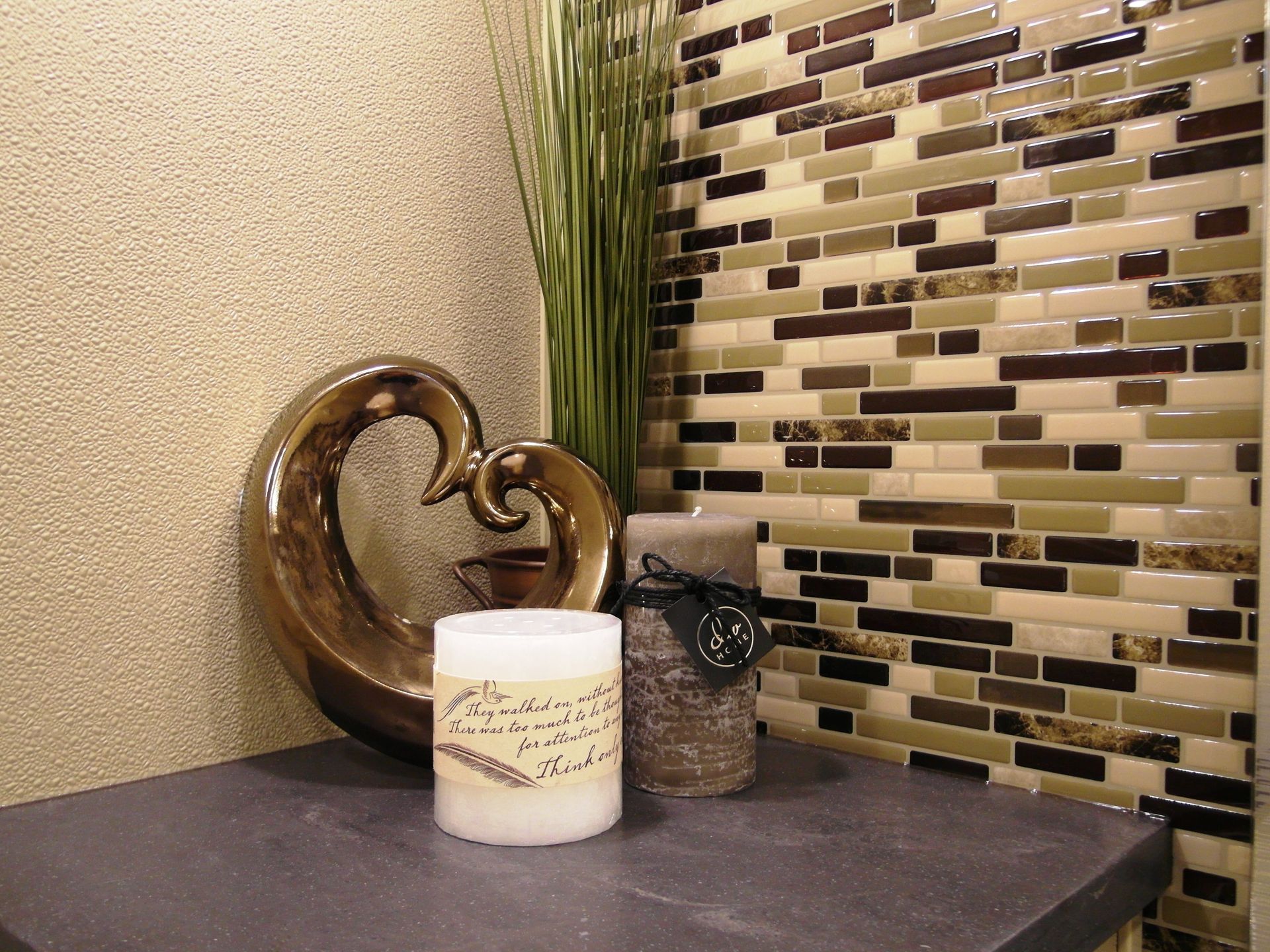 A candle is sitting on a table in front of a tiled wall.