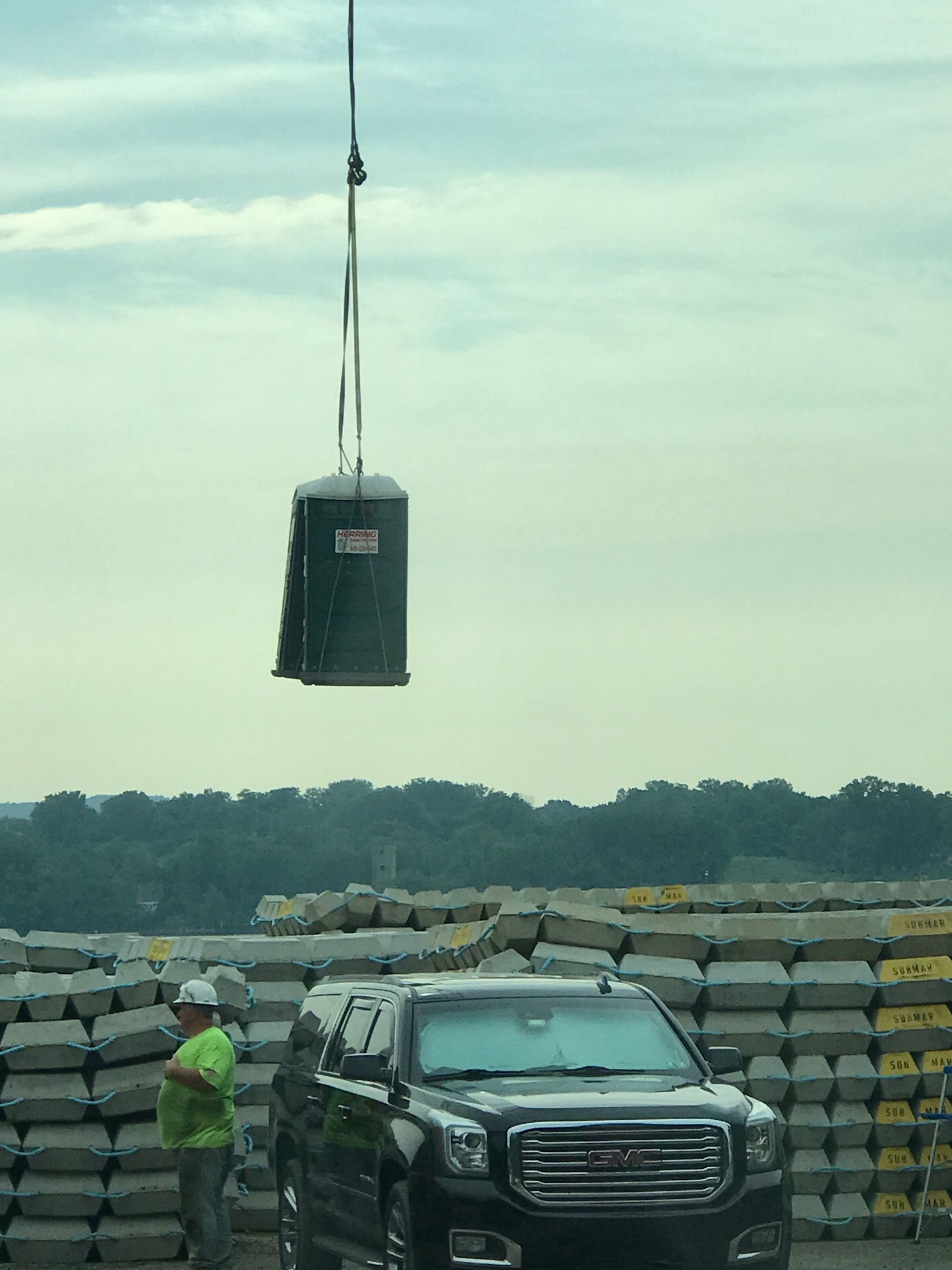 A truck is being lifted by a crane in front of a pile of bags.