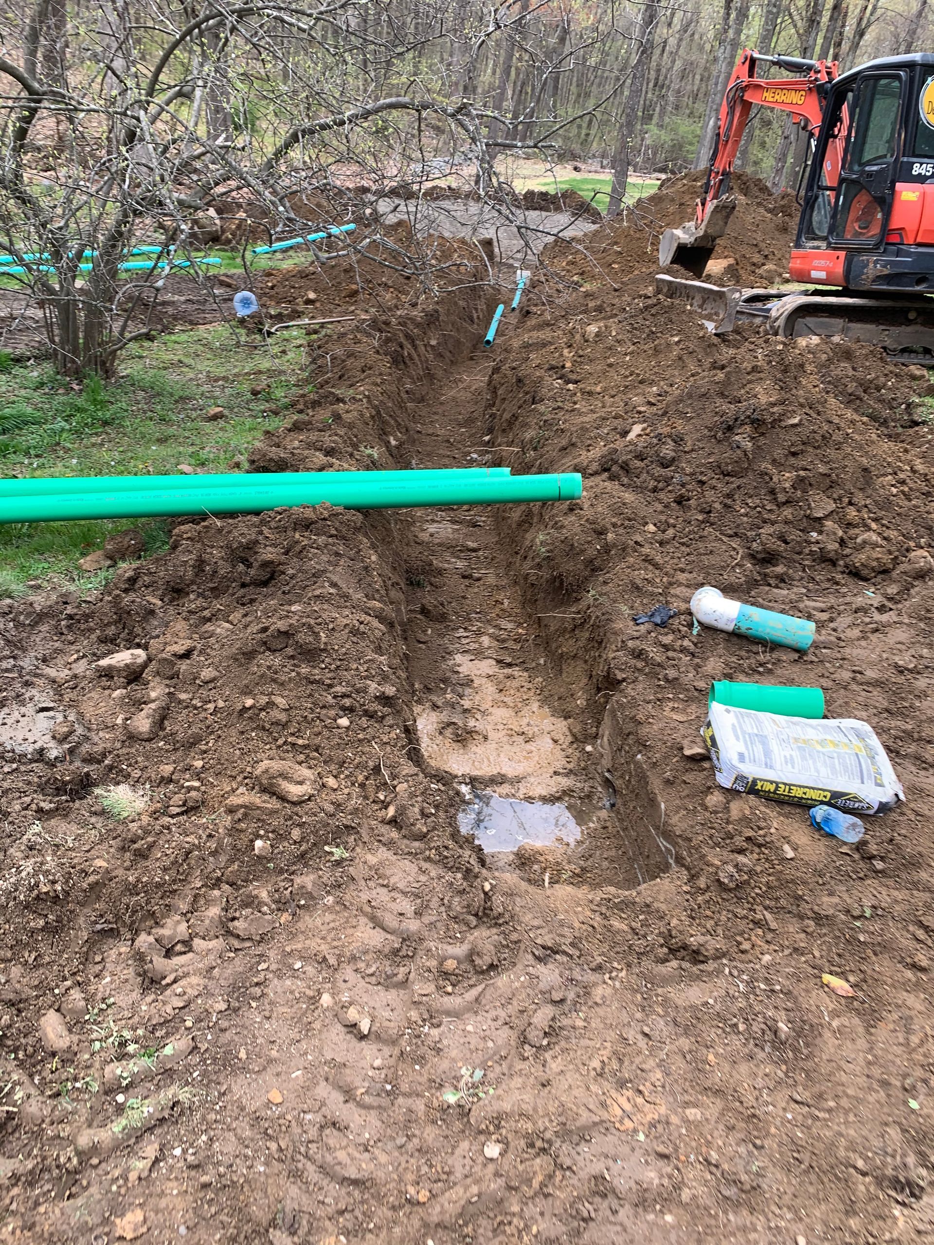 A green pipe is laying in the dirt next to a bulldozer.