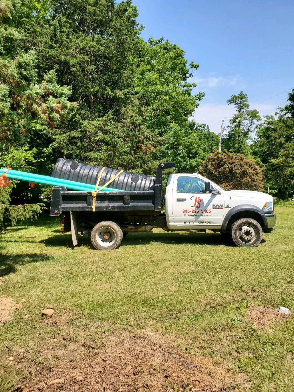 A white dump truck is parked in a grassy field.