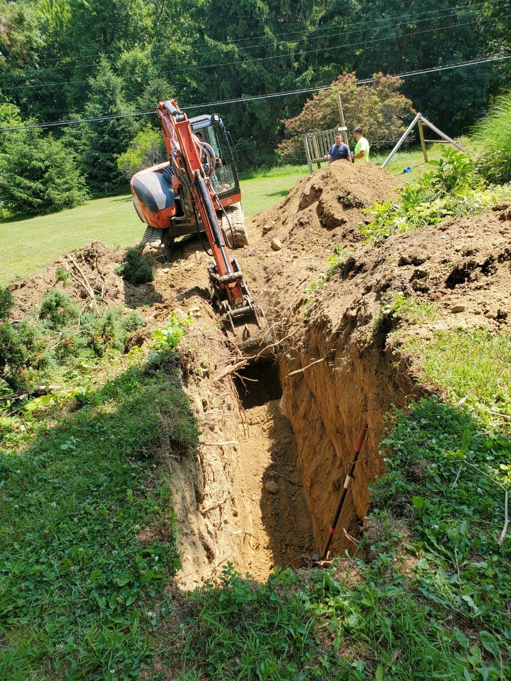 An excavator is digging a hole in the ground in a yard.