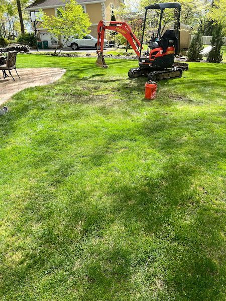 A small excavator is sitting in the middle of a lush green lawn.