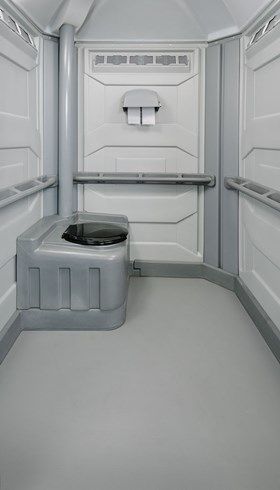The inside of a portable toilet with a toilet and a paper towel dispenser.