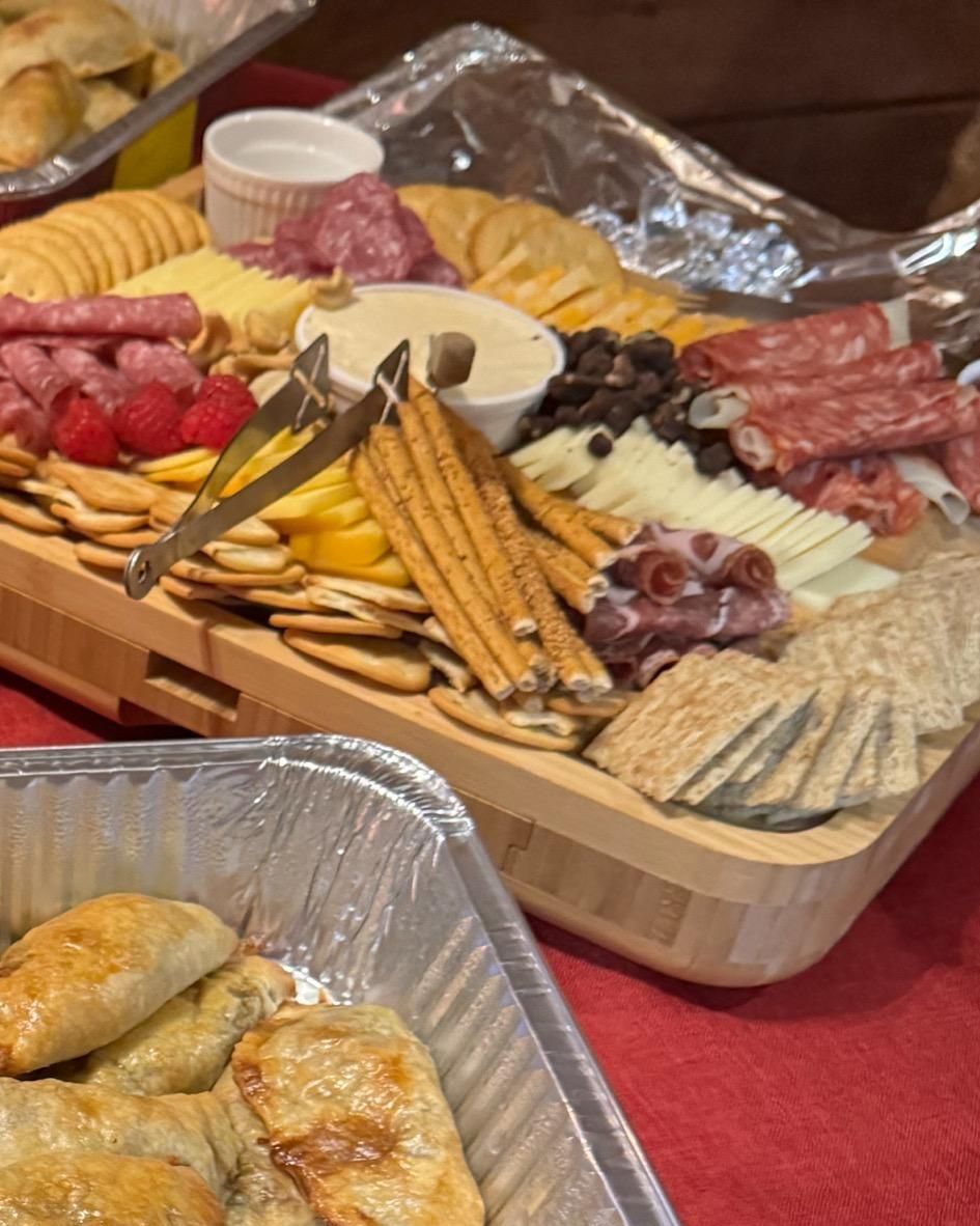 A wooden tray filled with crackers , cheese , and meat.