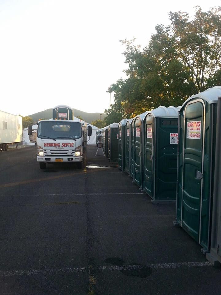 A row of portable toilets are lined up in a parking lot
