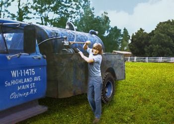 A woman is standing next to a blue truck that says wi-1147s