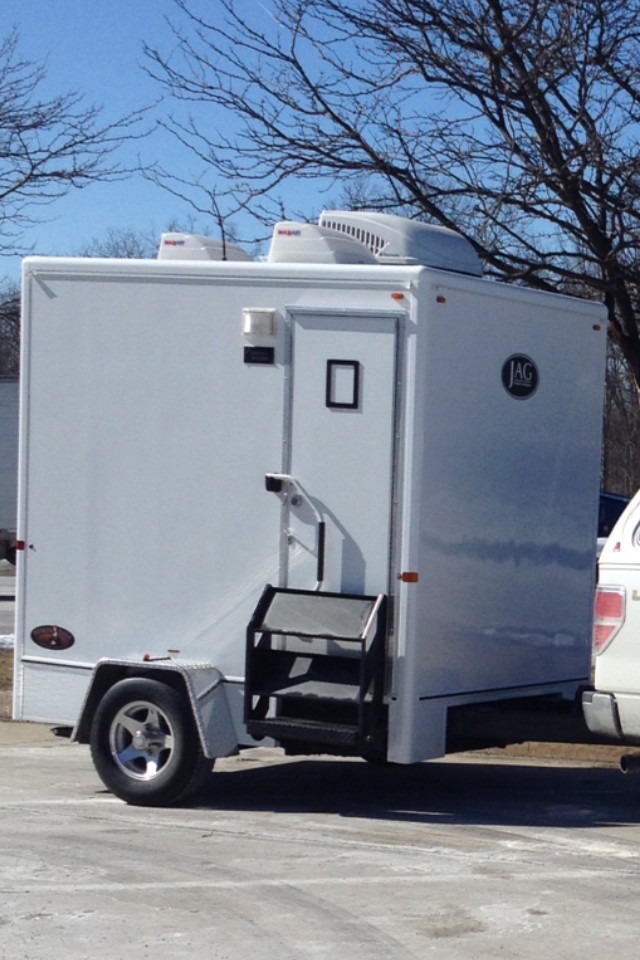 A white trailer is parked next to a white truck