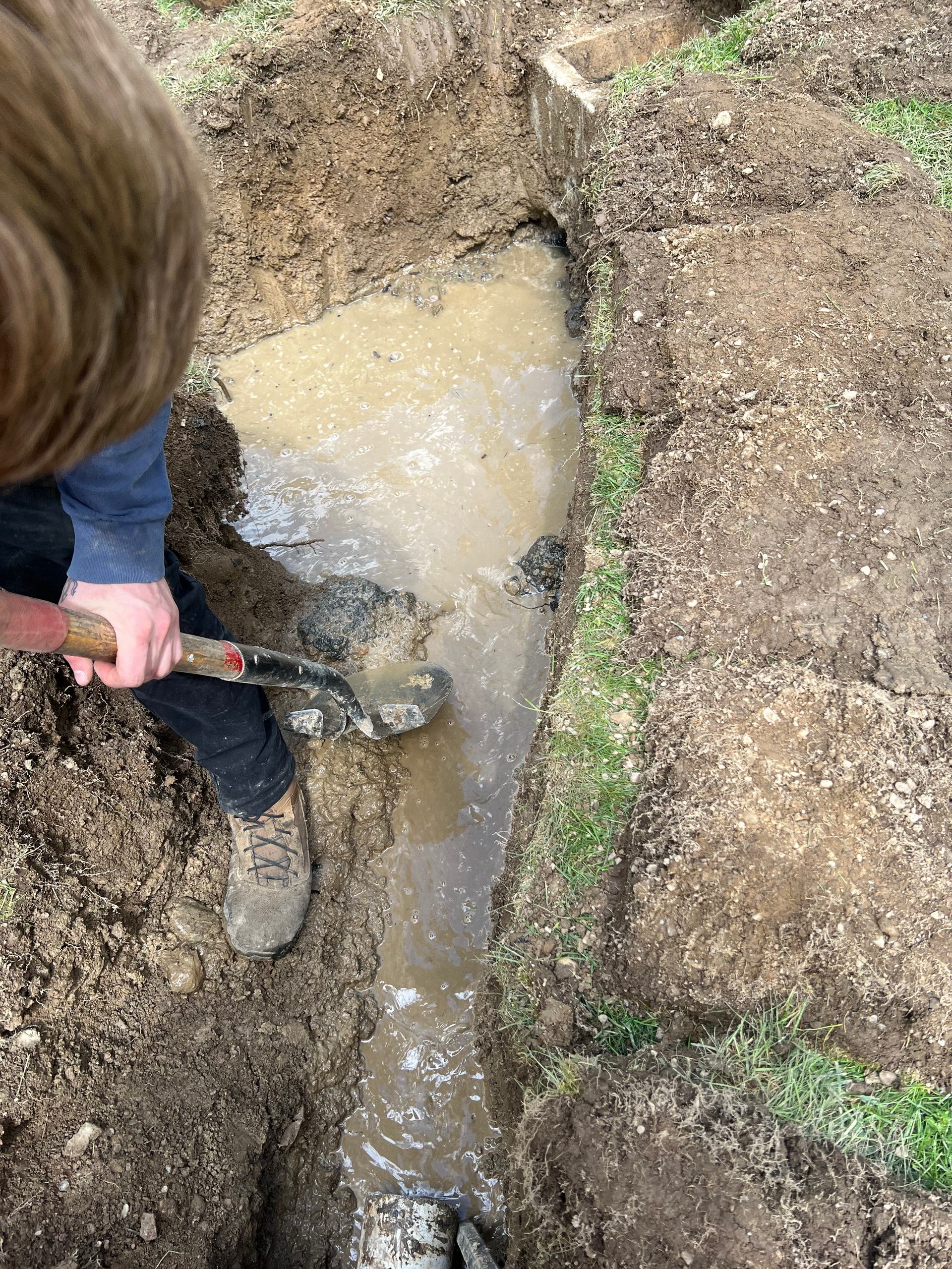 A young boy is digging in the dirt with a shovel.