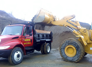 A kawasaki dump truck is being loaded with dirt