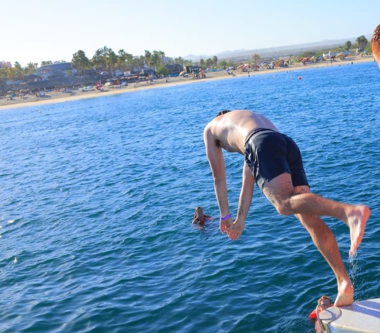 A man is jumping into the ocean from a boat