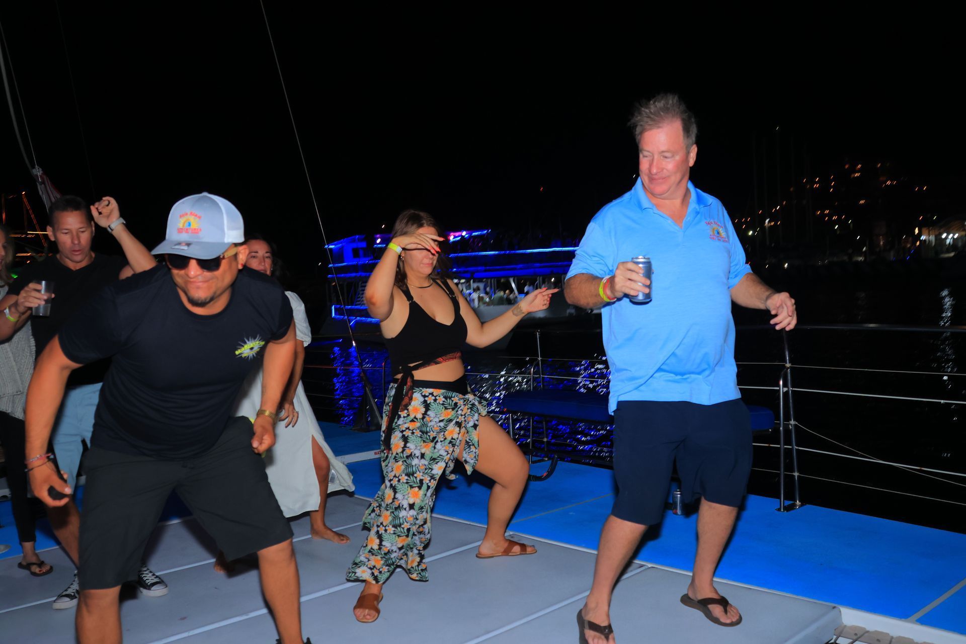 People dancing on a nighttime boat deck with city lights in the background