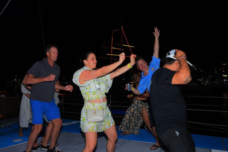 People dancing on a boat at night with city lights in the background