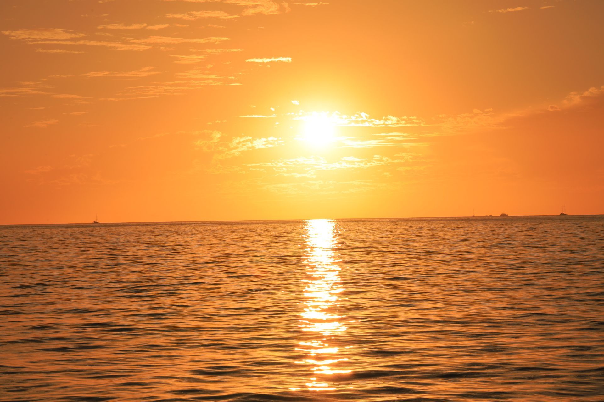 Orange sunset over calm ocean with sun reflecting on rippling water