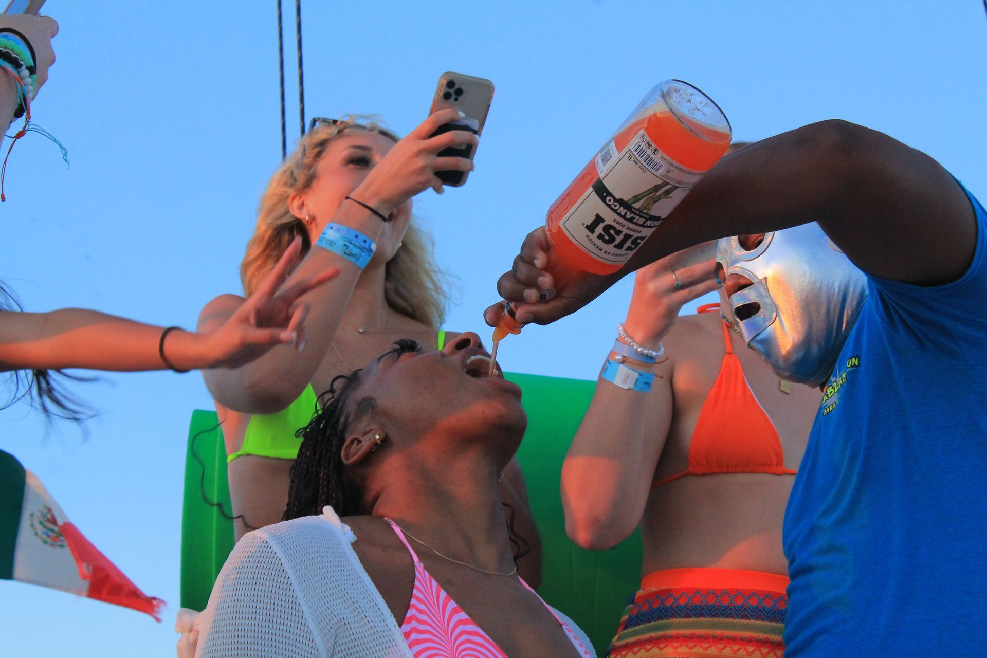 People at an outdoor party drinking from bottles and a can under a blue sky