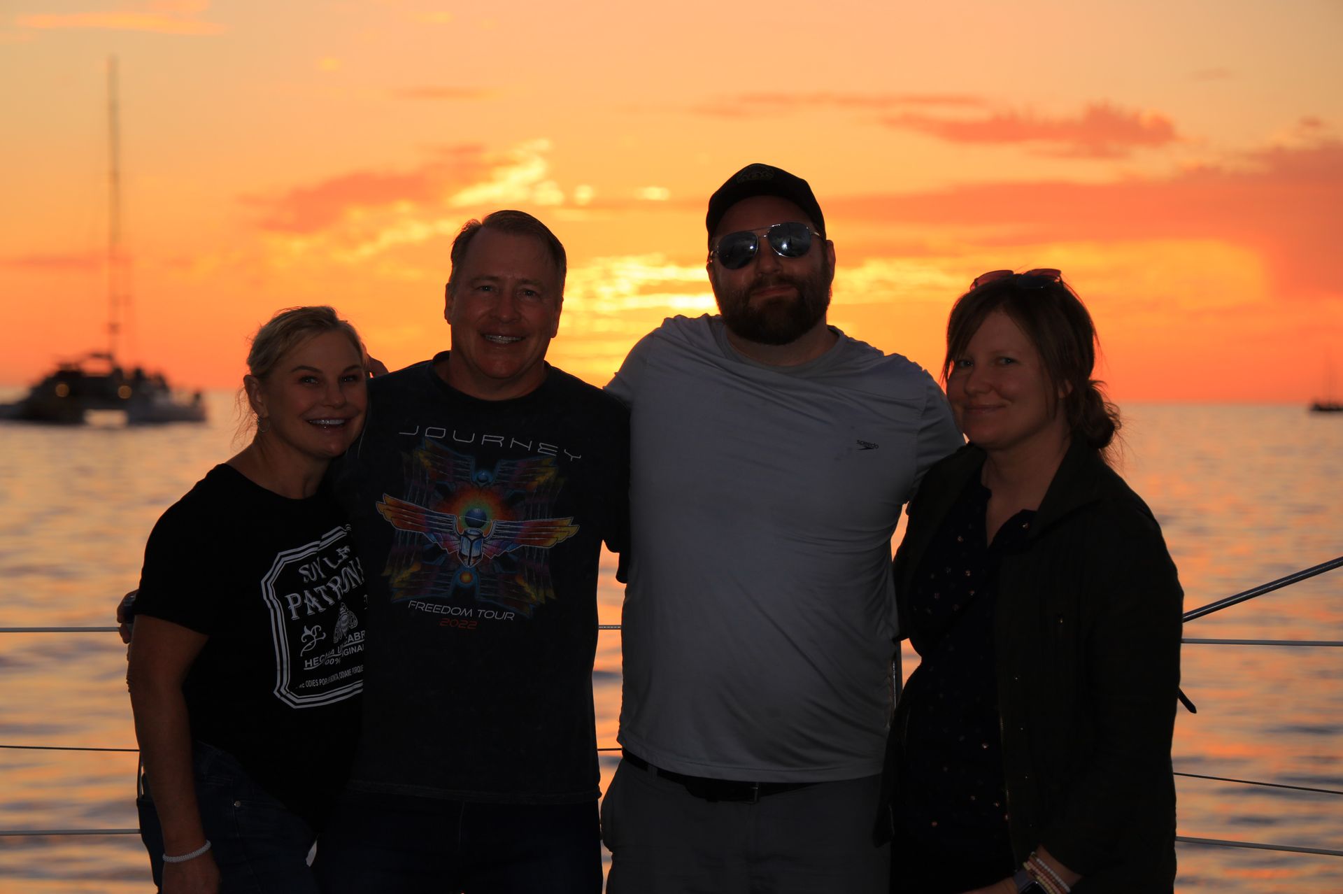 A group of people are posing for a picture in front of the ocean at sunset.