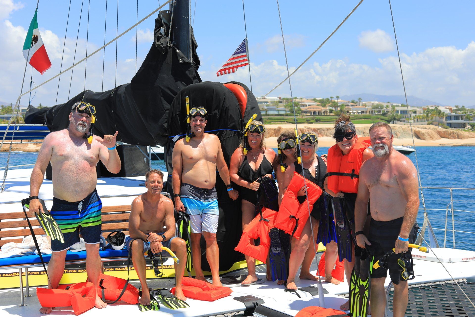 People posing on a sailboat deck in bright life jackets on a sunny day at sea
