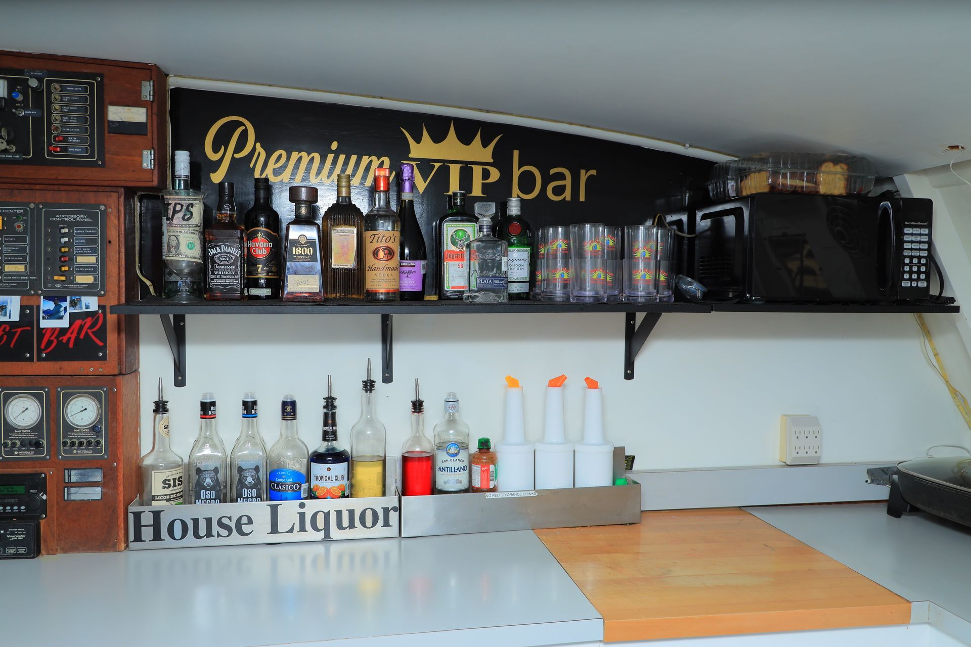 Home bar shelf with liquor bottles, glasses, and a “Premium VIP bar” sign above a countertop