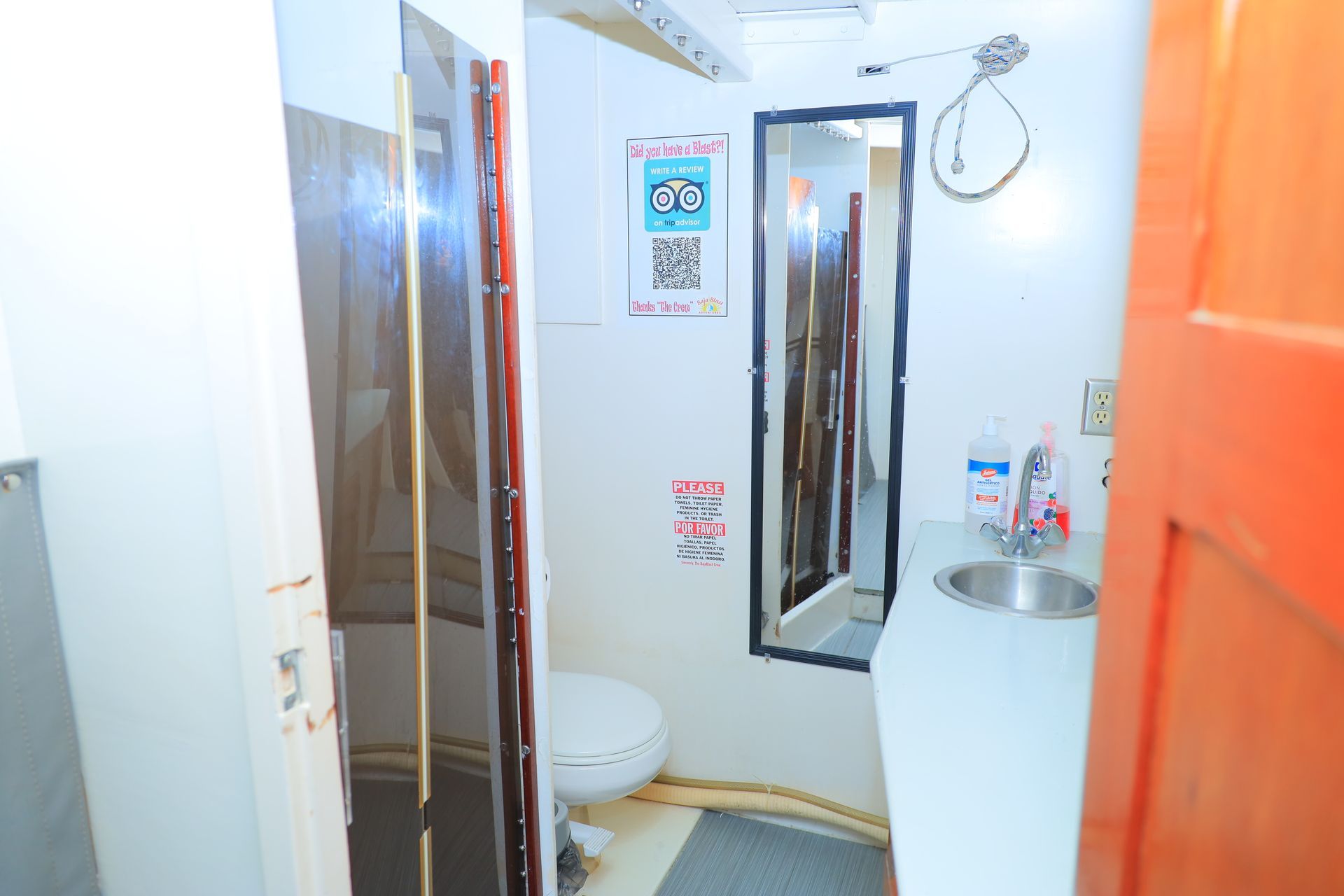Small bathroom with toilet, sink, mirror, and shower stall, viewed from the doorway.