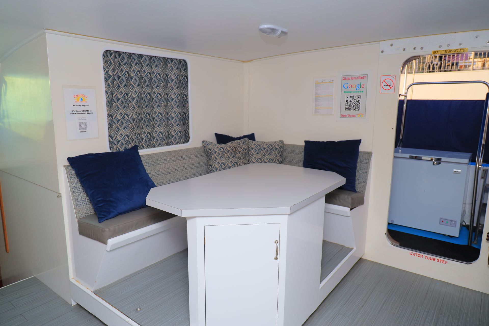 Cozy white booth seating with blue cushions and built-in table in a small cabin lounge