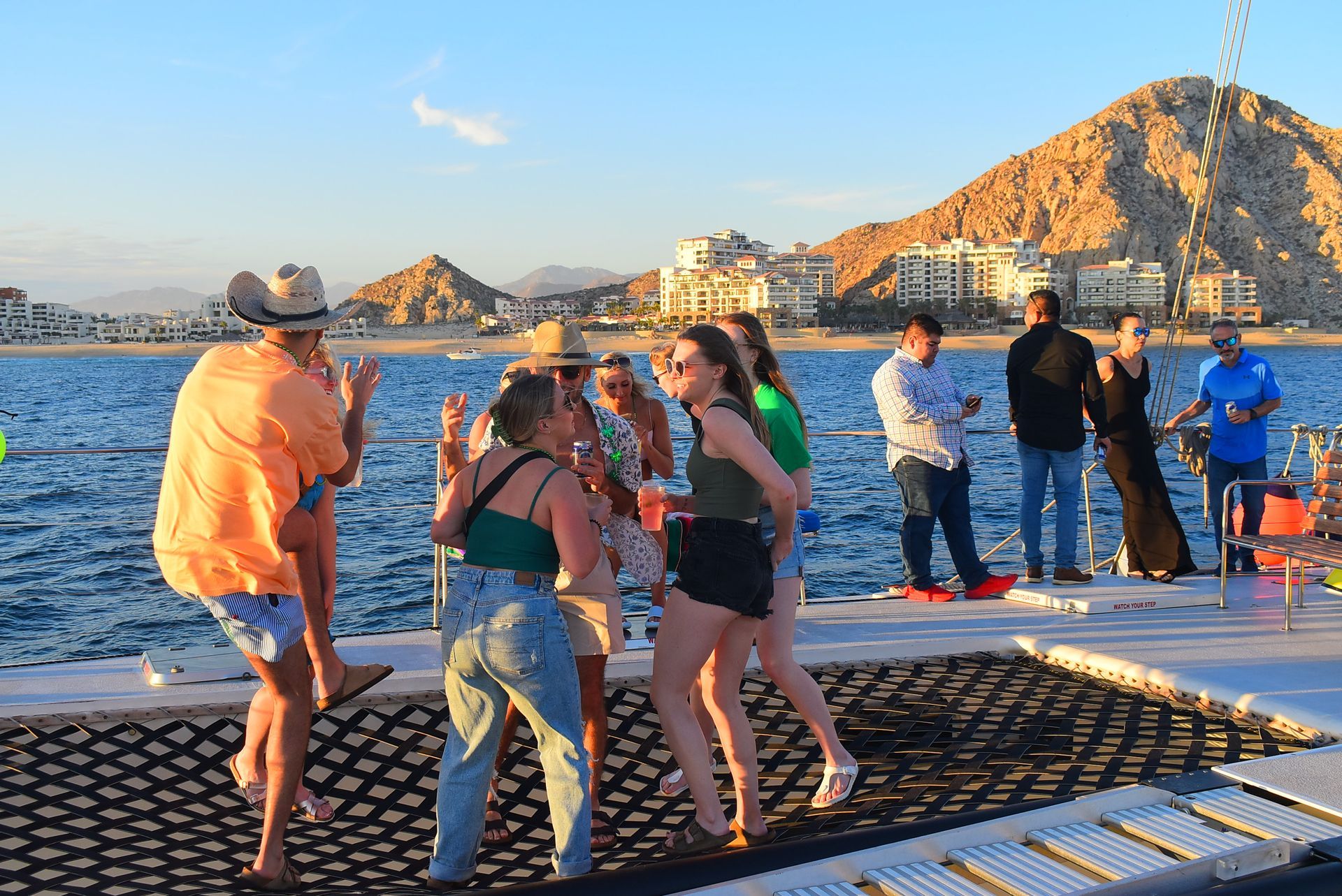 People socializing on a floating dock at sunset with water and mountains in the background