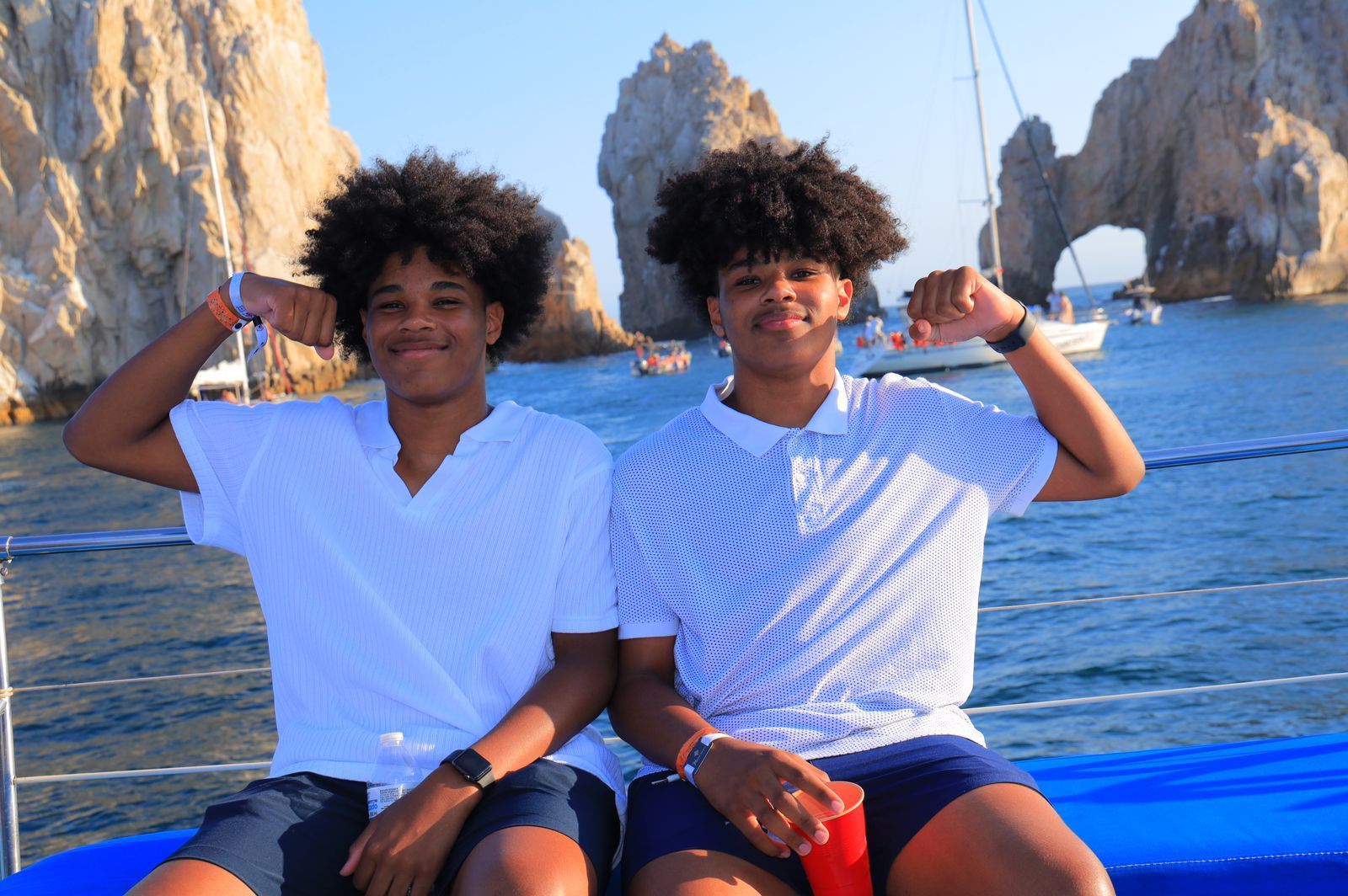 Two young men are sitting on a boat in the ocean.