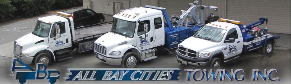 Three tow trucks in a row, white and blue, parked in front of a gray wall, logo at the bottom.