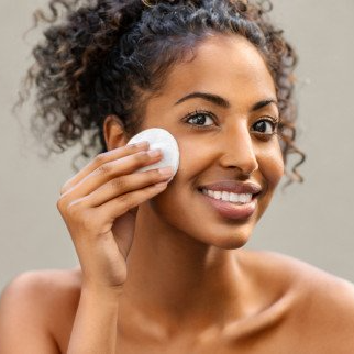 a woman applying skin care with a cotton pad