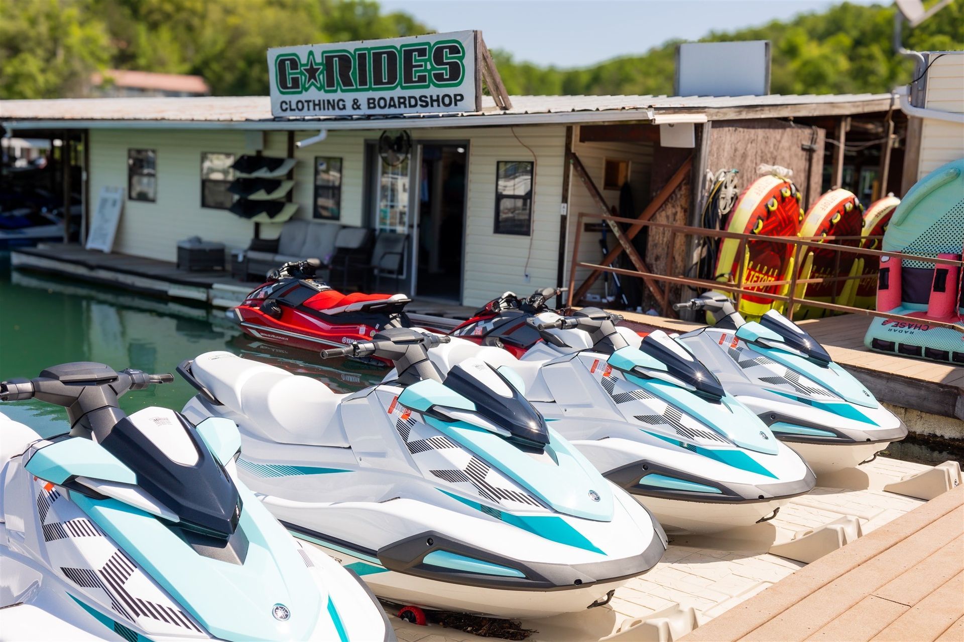 Several jet skis are parked in front of a store called tides