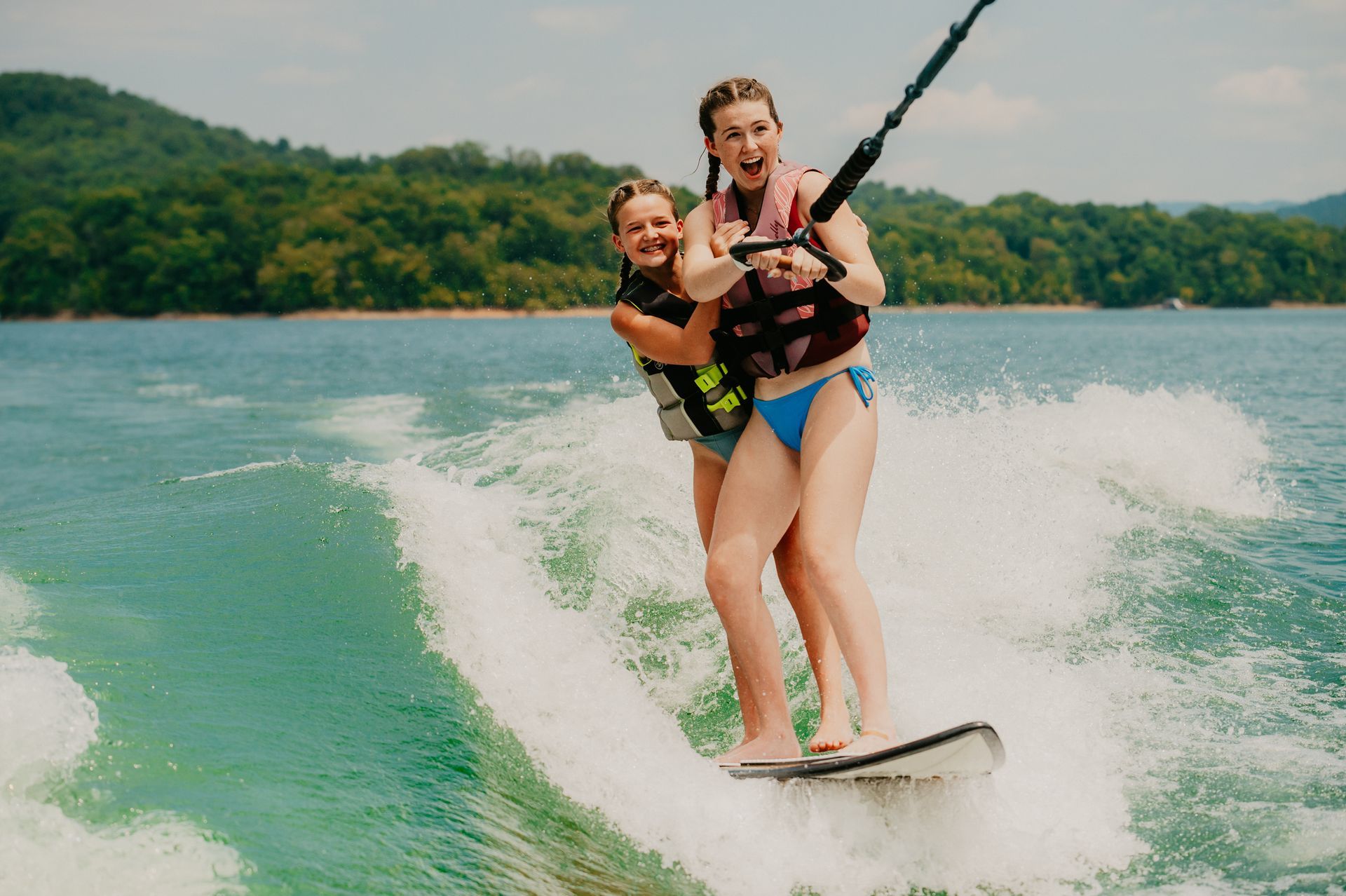 Two girls on a wakeboard on the lake.