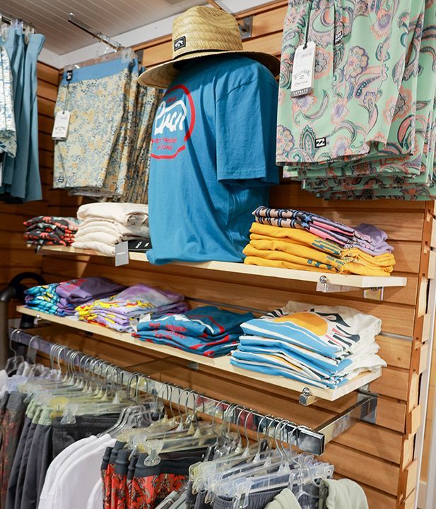 A variety of clothes are hanging on a wall in a store
