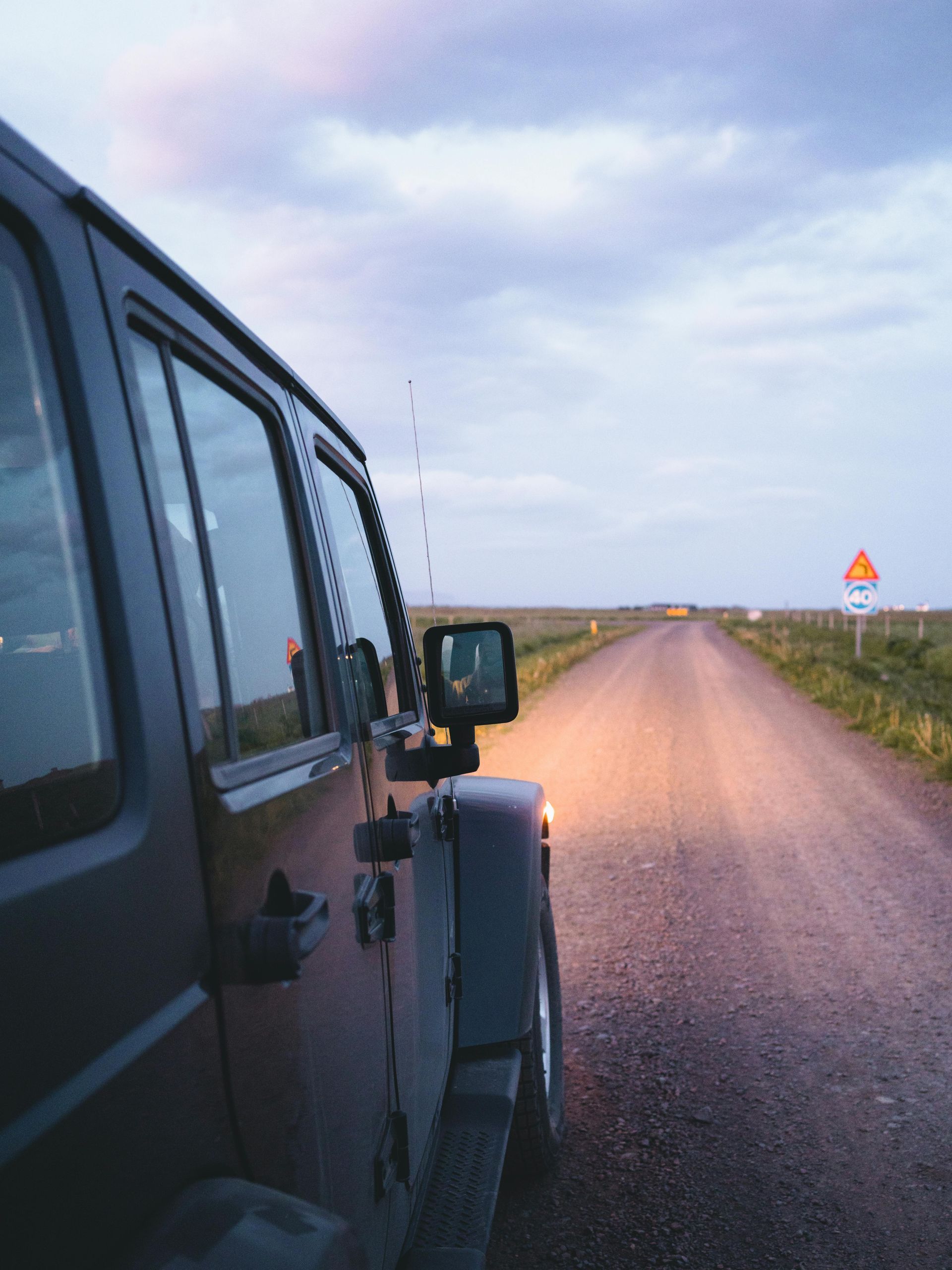 A jeep is parked on the side of a dirt road