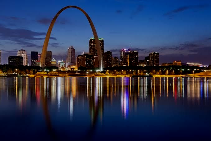 St. Louis Gateway Arch at dusk with city skyline and reflections on the river