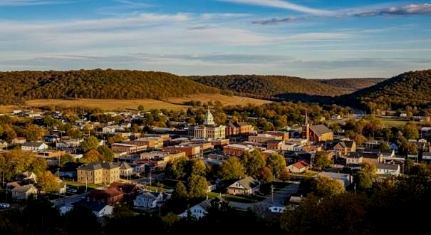 Aerial view of a small town with colorful houses nestled among hills under a clear sky.