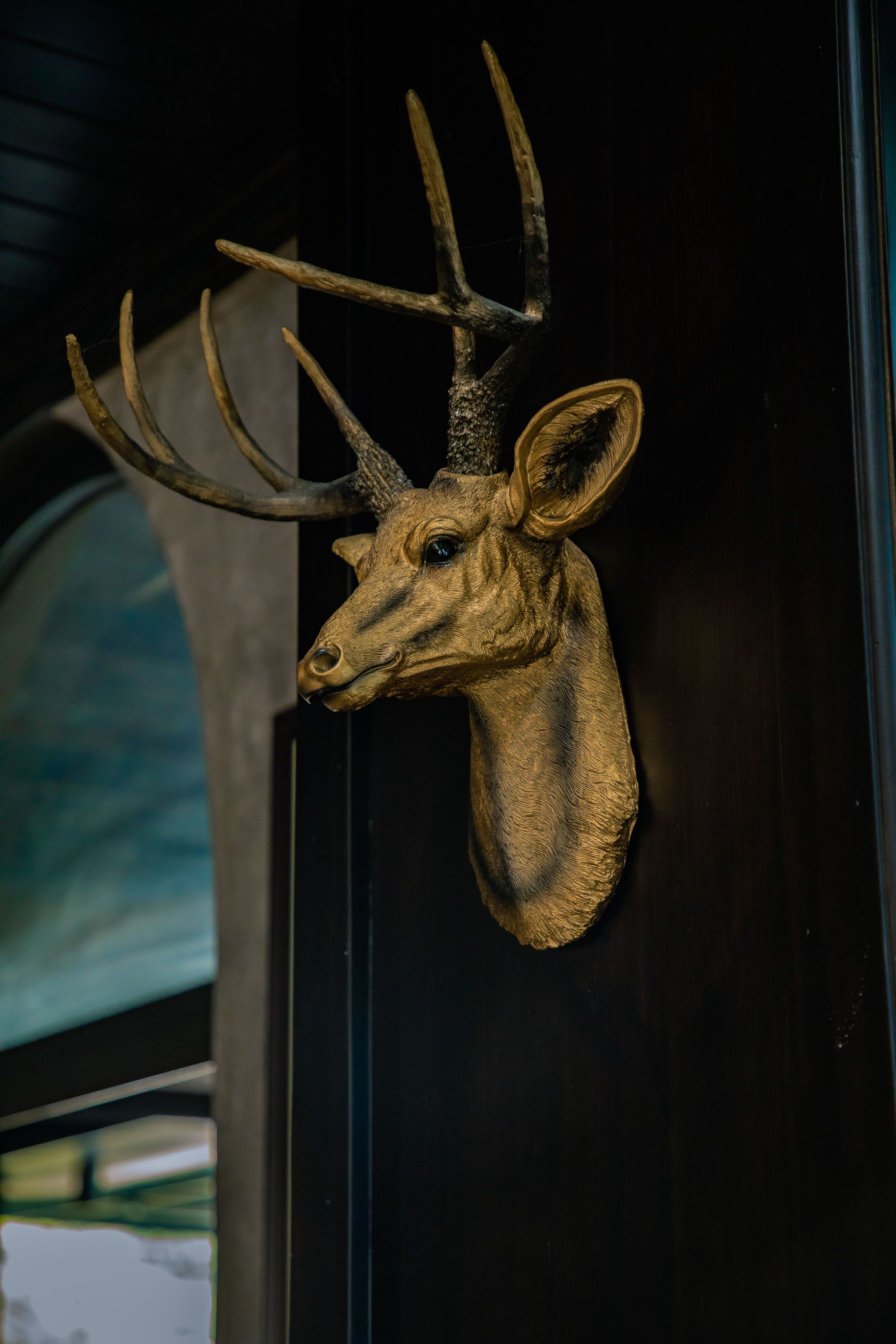 Mounted deer head sculpture on a dark wall in a dimly lit interior